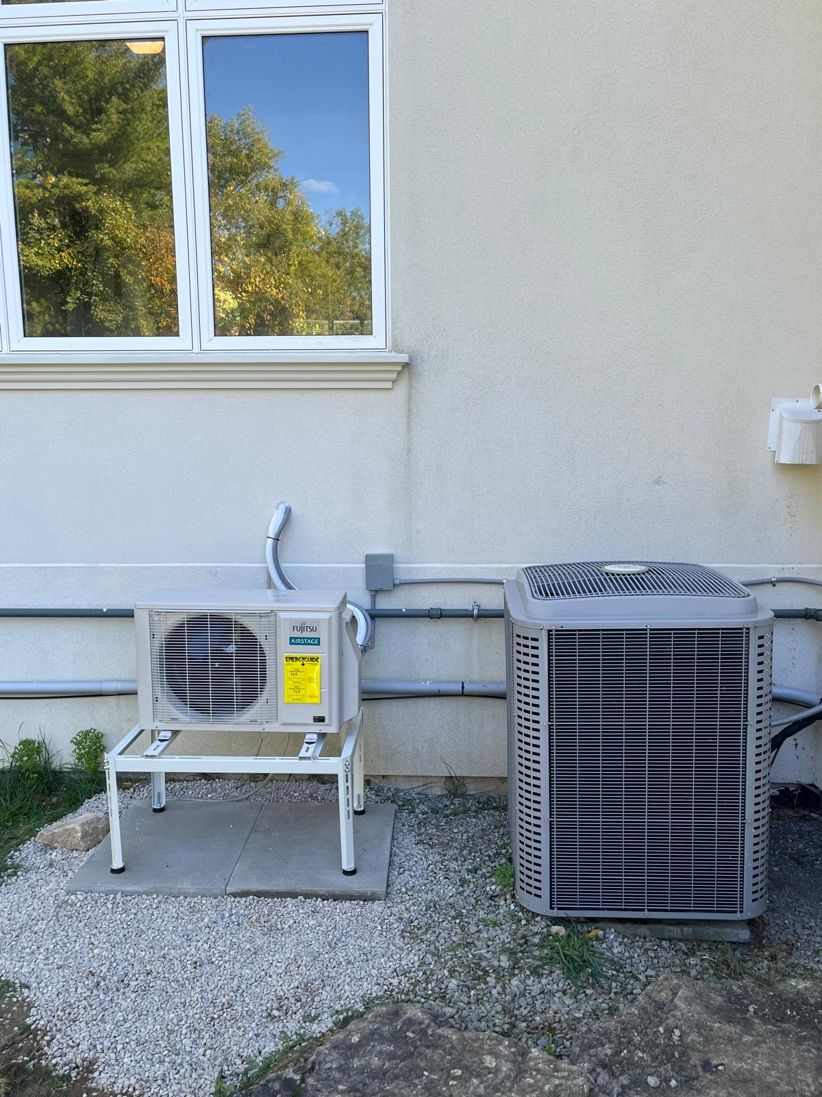 Fujitsu Airstage cold-climate heat pump installed beside a central AC condenser by IKAD Mechanical in Halton